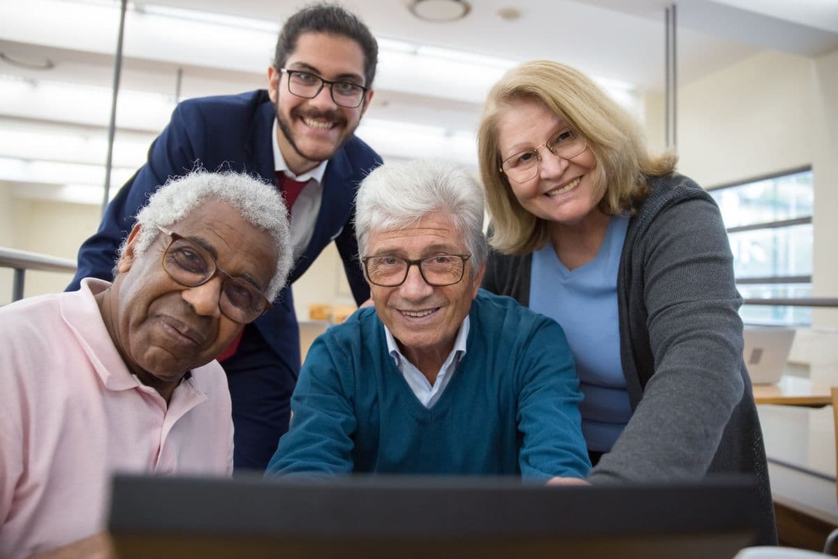 Older adults gathered around a table in a senior center activity room, engaged and smiling