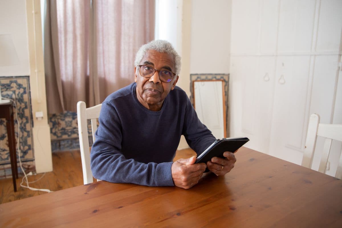 An older woman speaking to Amka on a tablet, mid-conversation and smiling